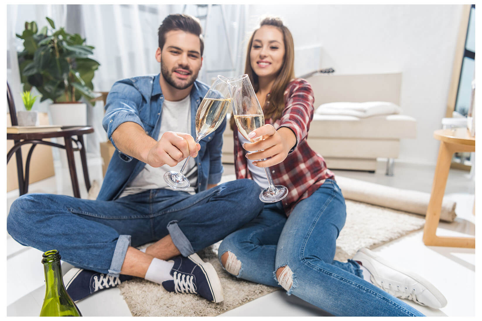 Young couple toasting with drinks in their new home